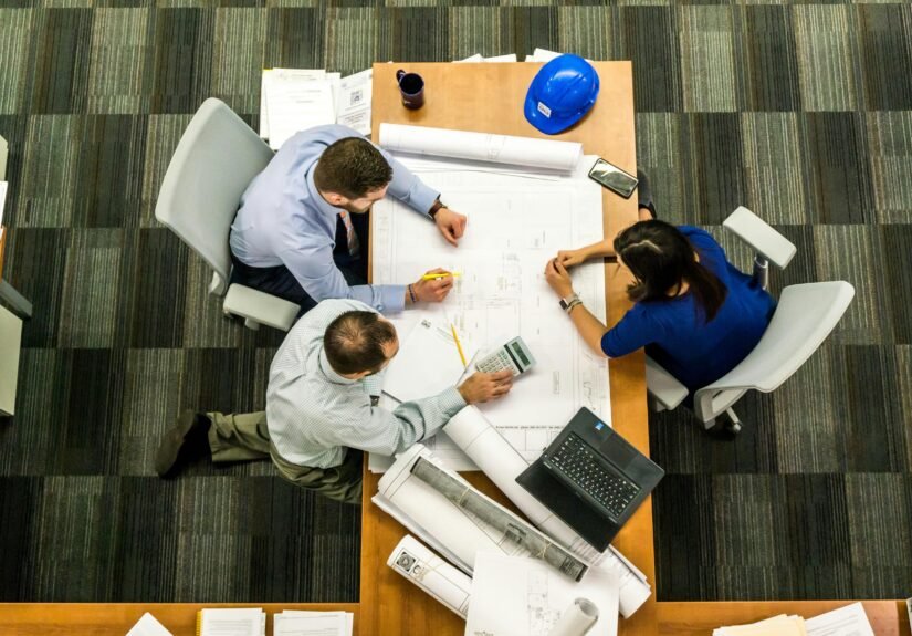 Top view of a team working on construction plans in an office setting.